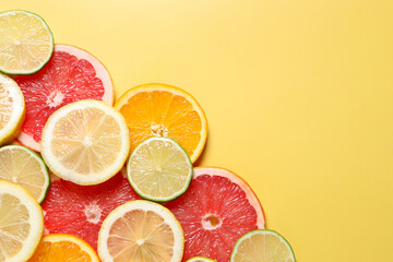 Different sliced citrus fruits on yellow table, top view. Space for text