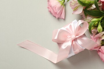Happy Mother's Day. Beautiful flowers and gift box on light grey background, flat lay. Space for text
