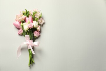 Happy Mother's Day. Bouquet of beautiful flowers tied with pink ribbon on light grey background, top view. Space for text
