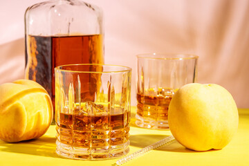 Alcoholic drink in a glass with a peach on a bright background. Summer party concept.