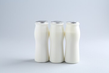Tasty yogurt in bottles on light grey background