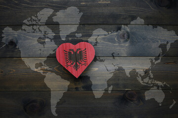 wooden heart with national flag of albania near world map on the wooden background. - obrazy, fototapety, plakaty
