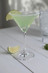 Delicious Margarita cocktail in glass and lime on white wooden table