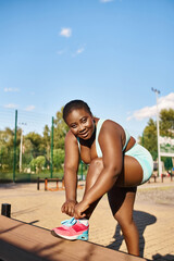 An African American woman with a curvy body, in sportswear, tying her shoe while enjoying the outdoors.