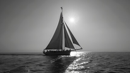 A sleek sailboat cuts through the waves in the open ocean in a black and white photo
