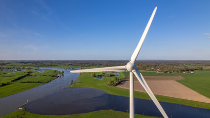 Closeup of wind turbine in The Netherlands part of sustainable industry Dutch along river IJssel and Twentekanaal waterway picturesque landscape. Aerial circular economy future concept