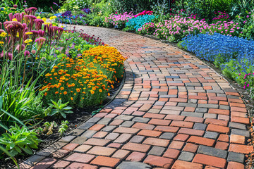 Red brick road in garden with different colorful flowers