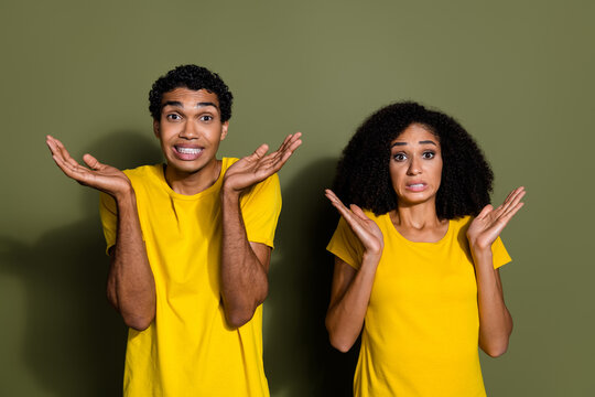 Photo of two young people shrug shoulders wear t-shirt isolated on khaki color background