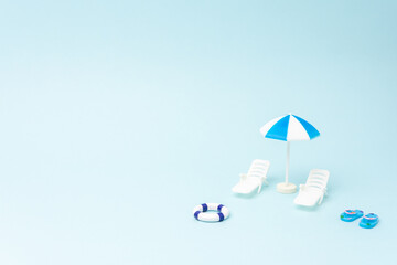 Creative background with sunbeds and sun umbrella on pastel blue background. Summer holiday concept.