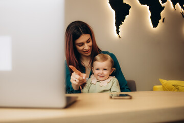 mother shows her daughter vacation options on a laptop in a travel agency