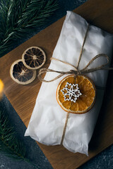 A gift wrapped in kraft paper tied with a rope Christmas stollen decorated with dried orange fruits and spruce branch. New Year holiday baking. Wrapped traditional Christmas cake. Top view