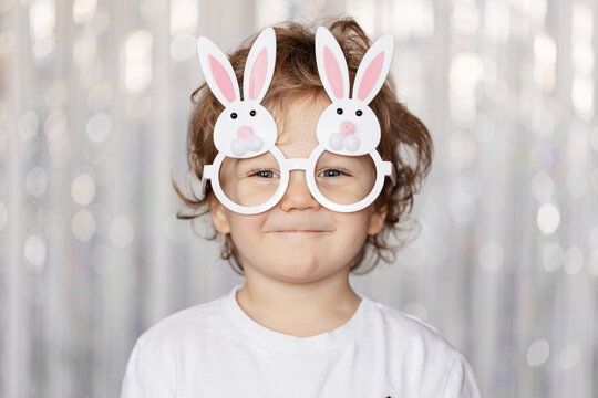 Cute little blond boy wearing glasses in the shape of bunny ears for Easter