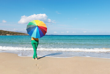 Young woman with colorful umbrella on the beach. Summer concept.