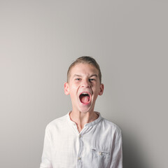 Screaming teenager boy in a white shirt on bright background.