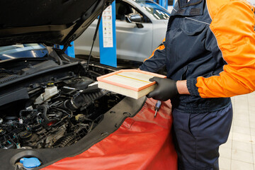 Professional mechanic man holding air filter of a car for repair and preventive maintenance car in...