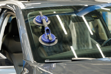 Automobile special workers replacing windscreen or windshield of a car in auto service station...