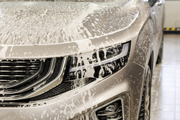 luxury SUV with laser headlights on in car shampoo and foam at car wash