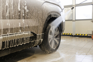 car wheel washed in self service carwash, brush cleaning aluminium rim disc covered in shampoo