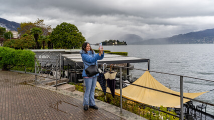 beautiful middle aged woman using mobile phone to take photographs outdoors in the rain
