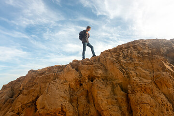 Male hiker with backpack walking up a rocky mountain trail