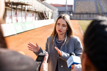 Two organization representative answer press questions and give interview on a soccer stadium....