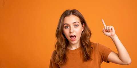 Obraz premium Close up photo of pretty cheerful lady stylish orange clothes arm direct empty space. surprised and joyfully shocked shows finger. isolated on orange color background. copy space