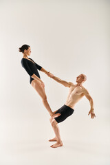 A shirtless young man and a young woman engage in an acrobatic dance, appearing to defy gravity...