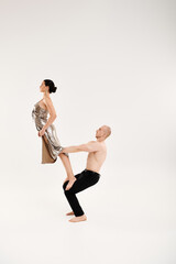 Fototapeta na wymiar A shirtless man and a woman in a shiny dress doing acrobatic element in a studio setting.