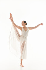 A young woman gracefully dances in a long white dress against a white background in a studio setting.
