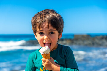 A young boy is holding an ice cream cone and smiling