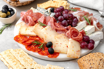 Charcuterie plate with Italian salami and prosciutto ham, with gorgonzola cheese and pecorino cheese with herbs, served with olives and grapes. appetizer platter for aperitif