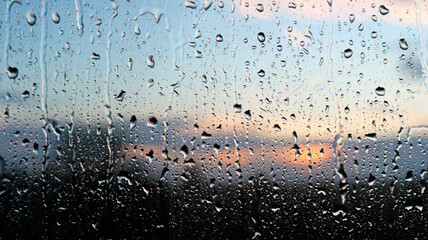 Stunning photoshoot of raindrops on a window with background of sunset in the sky. Wallpaper image...
