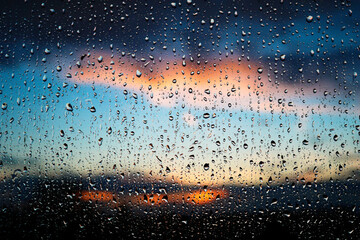 Stunning photoshoot of raindrops on a window with background of sunset in the sky. Wallpaper image...