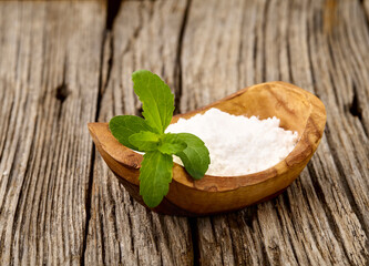 Stevia rebaudiana, sweet leaf sugar substitute isolated in wooden bowl on wooden background