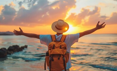 A traveler with arms outstretched overlooking the sea at sunset, back view. Man wearing hat and backpack and enjoying vacation on summer holiday by seaside