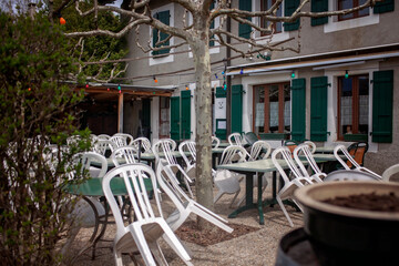 A quiet village cafe afternoon rush, its empty white chairs create a tranquil atmosphere. The...