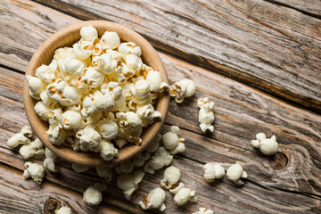 Wooden bowl with salted popcorn on wooden table. Top view.