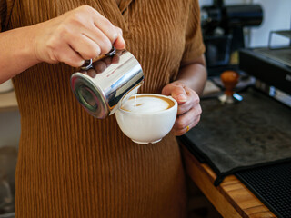Barista pouring milk into coffee making a cappuccino. Barista making cappuccino,Professional bartender preparing coffee drink
