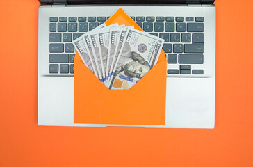 laptop and orange envelope with dollars