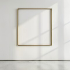 An empty gold gilded frame hanging on a white concrete wall with soft lighting and shadows from the window on the right.