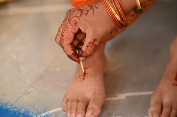 Applying Hindu Swastik on leg. a Swastik As Symbol Of Sun. Hindu Religion. Red ink. Woman indian...