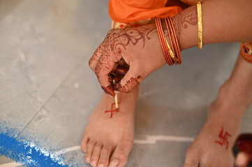 Applying Hindu Swastik on leg. a Swastik As Symbol Of Sun. Hindu Religion. Worship. Red ink. Woman...