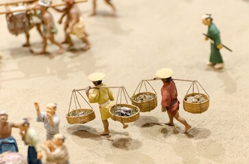 A group of people are carrying baskets of fish on a beach