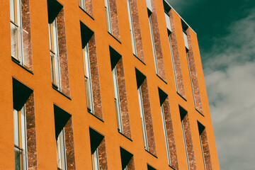 Fragment of an orange house facade with long narrow windows. High rise apartment or office building...