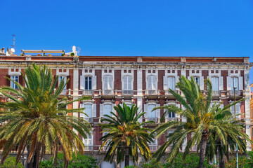 Fototapeta na wymiar Cagliari waterfront historic buildings facade with wooden window shutters and iron balconies under clear blue sky in Sardinia Island, Italy.