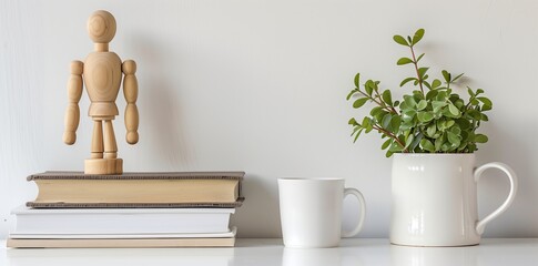 white frame background, a small wooden mannequin doll next to a stack of books and a coffee mug on a white table top, modern home decor, interior design