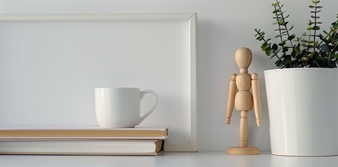 white frame background, a small wooden mannequin doll next to a stack of books and a coffee mug on a white table top - obrazy, fototapety, plakaty