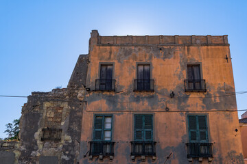 Fototapeta na wymiar Cagliari citadel old building facade with wooden window shutters, iron balconies and decayed facade in Sardinia Island, Italy.