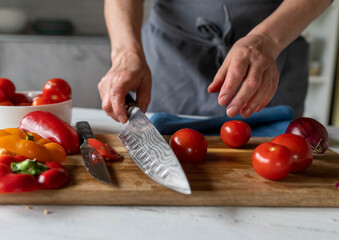 Woman with apron holding a kitchen knife in her hand for cutting vegetables