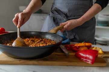 Woman ist stirring a pan with ready cooked meal